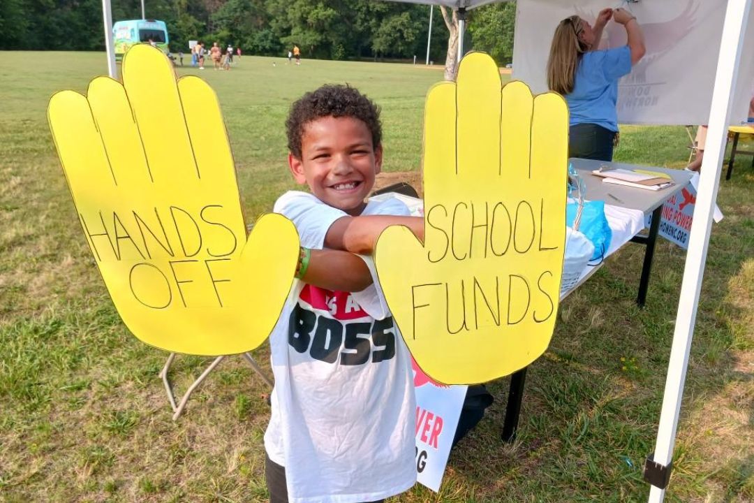 A boy holding up yellow hands with text on it