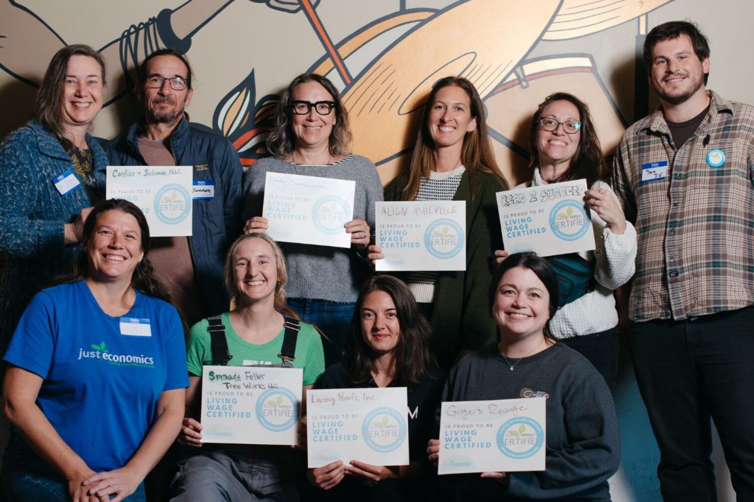 Two rows of people holding certificates that say "Living Wage Certified"