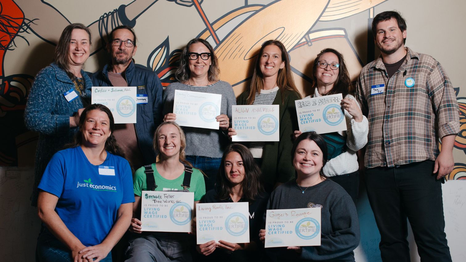 Two rows of people holding certificates that say "Living Wage Certified"