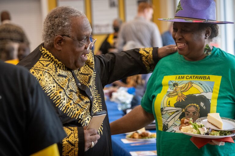 Two people smile and embrace at a community event