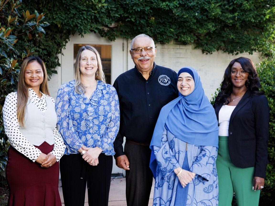 Five people stand in a row smiling for the camera
