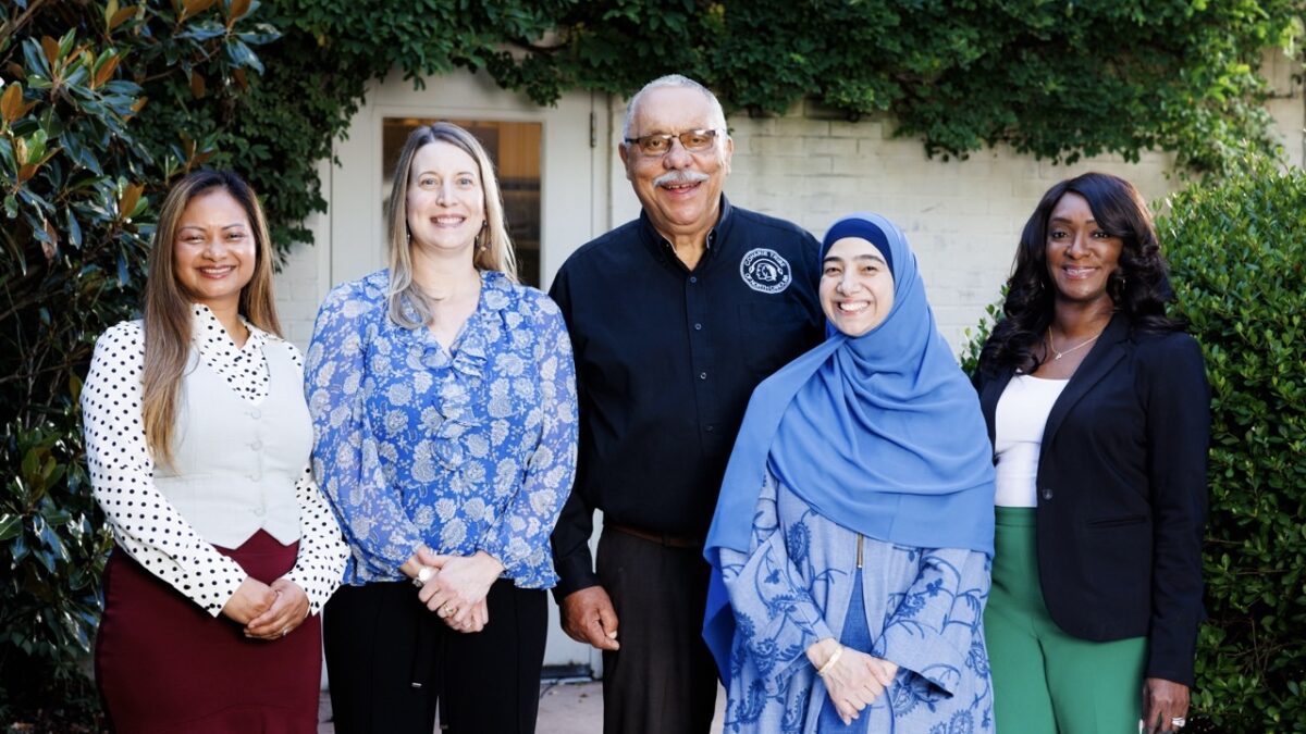 Five people stand in a row smiling for the camera