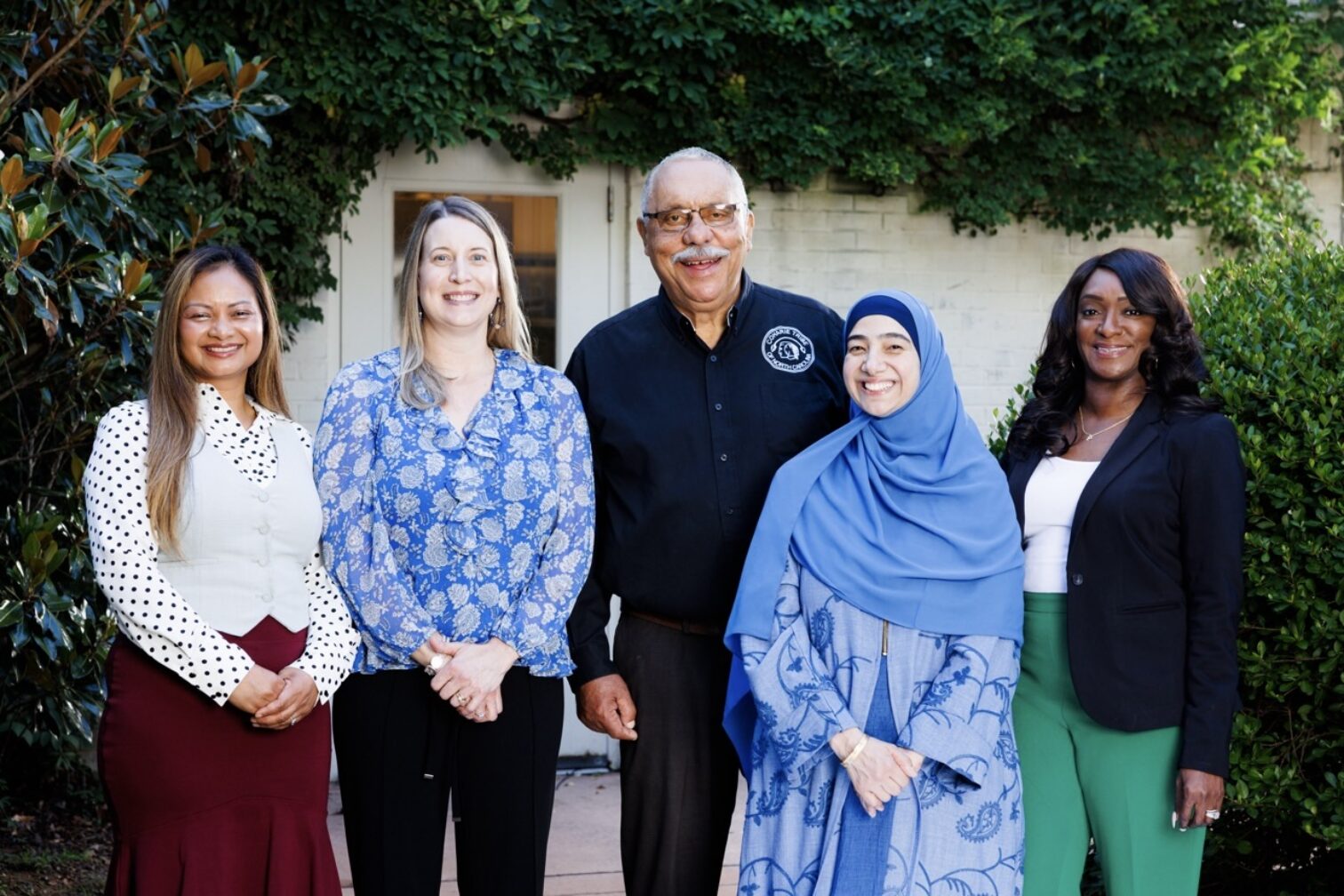 Five people stand in a row smiling for the camera