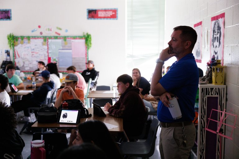 Principal observing students in a classroom with laptops and tablets